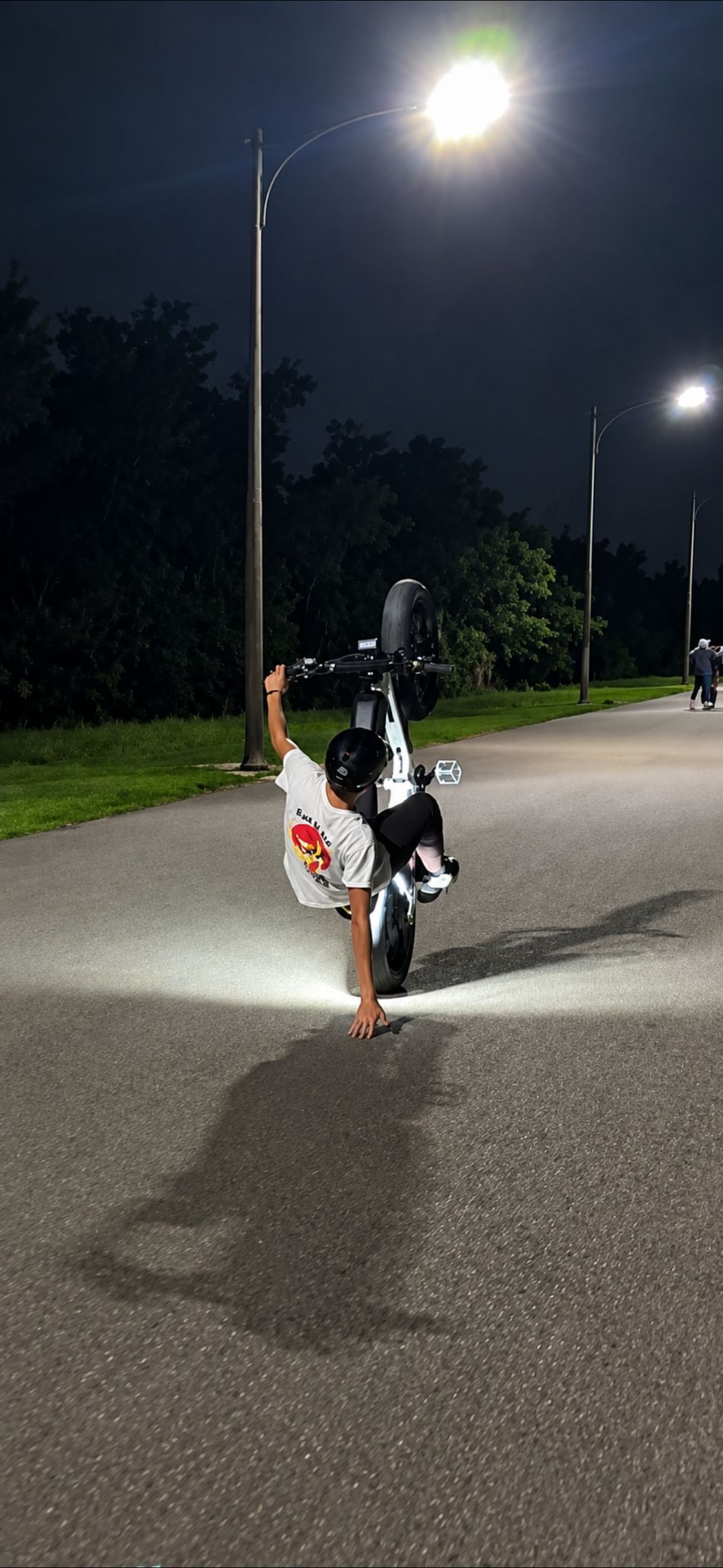Rider doing a wheelie at night on a Super 73 with WFD rock lights